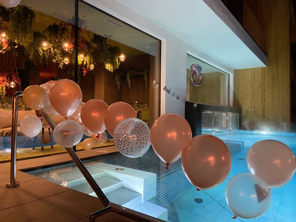 Dalla webcam il Latemar è bello, ma dal vivo è un sogno! Palloncini decorativi rosa e bianchi vicino a una piscina in un ambiente interno.