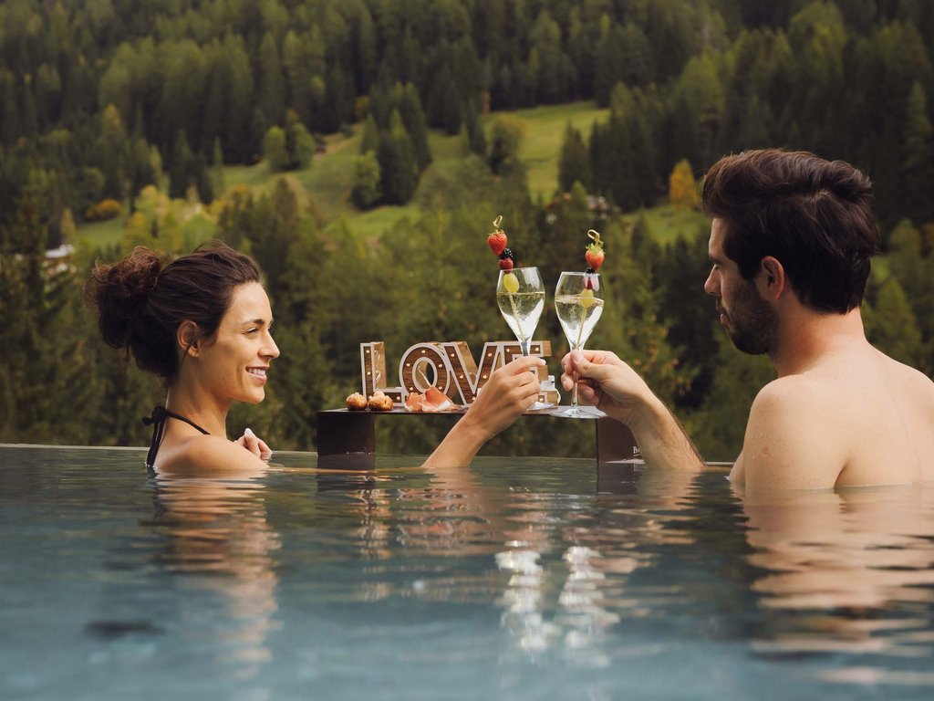 Sulla pista ciclabile, da Moena alla vostra oasi romantica Coppia si brinda in piscina con vista sulle montagne