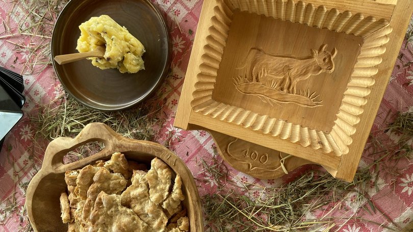 Escursioni da Moena e molto altro: il nostro programma Torta di pane croccante e burro su un tavolo rustico con erba e stampo in legno