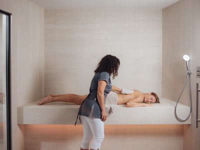 Al Latemar, dopo le passeggiate: relax nella Spa Oniro Massaggiatrice professionista che massaggia una donna distesa in una stanza luminosa