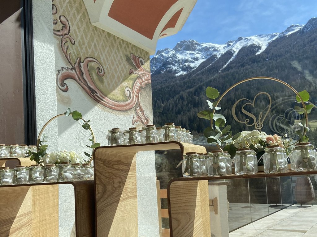 Dalla webcam il Latemar è bello, ma dal vivo è un sogno! Barattoli di vetro con decorazioni su tavoli di legno davanti a una finestra alpina