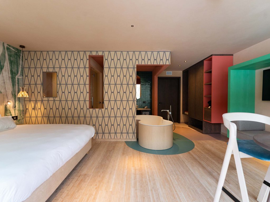 Albergo in Trentino vicino a Moena: Hotel Latemar Camera moderna con letto grande, vasca freestanding e area soggiorno colorata