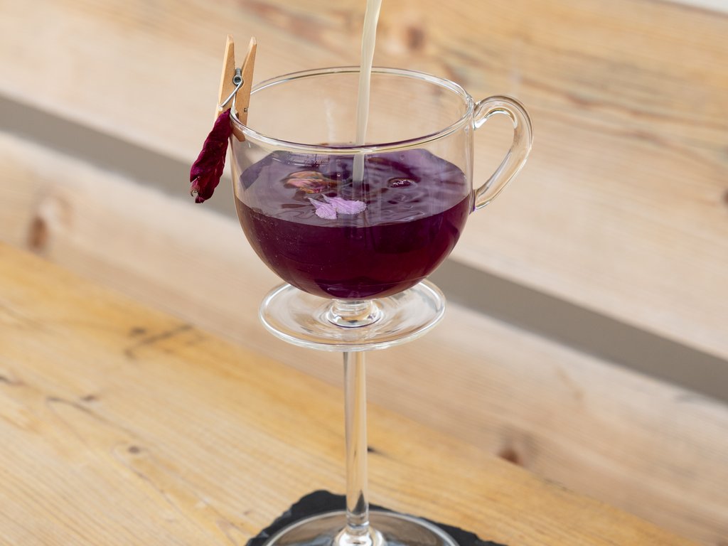 Val di Fassa e ciclabile: da ammirare dal cocktail & tea bar Versamento di liquido chiaro in una coppa di vetro con liquido viola e petalo