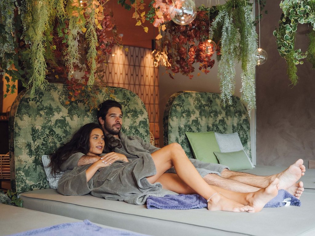 Al Latemar, dopo le passeggiate: relax nella Spa Oniro Coppia rilassata su lettini in spa con piante appese sopra