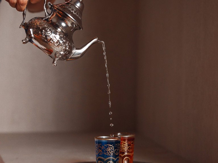 Il rituale dell’hammam al Latemar Hotel Persona versa tè da teiera decorata in bicchieri decorati su vassoio