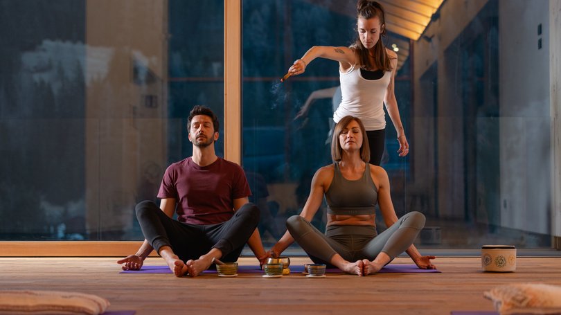Escursioni da Moena e molto altro: il nostro programma Due persone meditano mentre un'altra esegue una cerimonia di incenso in una sala