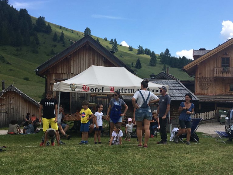 La pista ciclabile in Val di Fassa? C’è molto di più! Persone e bambini che giocano all'aperto davanti a hotel montano