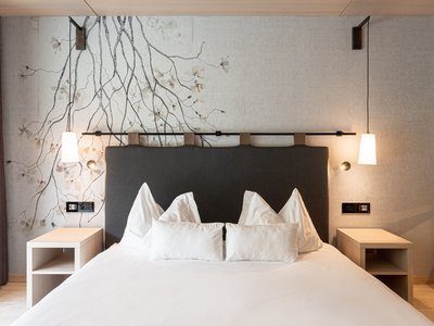Hotel a 3 stelle superior a Soraga in Val di Fassa: camere & suites Camera da letto moderna con letto matrimoniale, comodini e lampade a sospensione