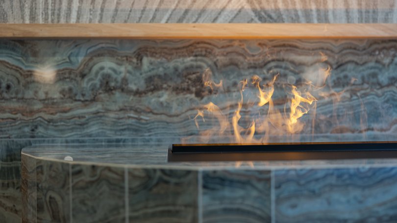 Moena, alberghi da sogno, panorama? C’è l’Hotel Latemar! Camino moderno in marmo con fiamme visibili in primo piano