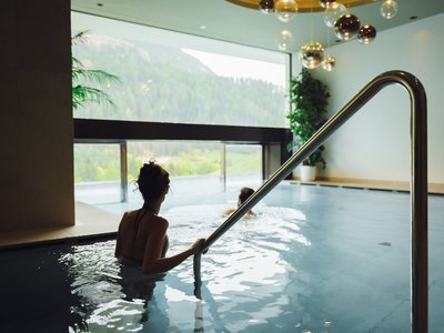 Hotel per disabili in Val di Fassa: il Latemar Due donne rilassate in una piscina interna con vista sulle montagne