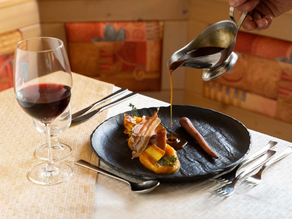 Ristorante a Soraga di Fassa: Mirage con #latermarview Piatto gourmet con salsa versata e bicchiere di vino rosso a tavola