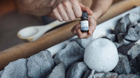 Meteo, Moena, Soraga, Latemar: tutto nella nostra gallery Mano che tiene una bottiglia di olio essenziale vicino a pietre e un pezzo di ghiaccio