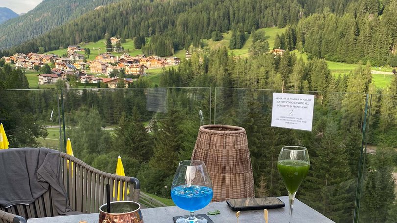 La pista ciclabile in Val di Fassa? C’è molto di più! Tavolo con aperitivi e antipasti con vista sulle montagne e villaggio
