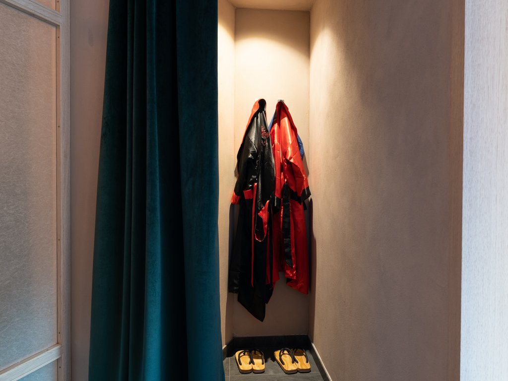 Soraga: dal lago alla piscina del Latemar Due kimono rossi e neri appesi con due paia di sandali in un angolo illuminato