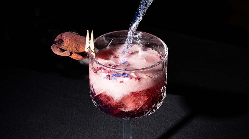 La pista ciclabile in Val di Fassa? C’è molto di più! Cocktail rosa con fiori secchi in bicchiere di cristallo su sfondo nero