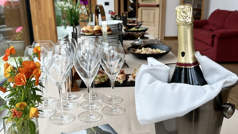 A Soraga il meteo è sempre ottimo per un Day Spa! Tavolo apparecchiato con bicchieri, fiori, champagne e cibo in un ambiente elegante