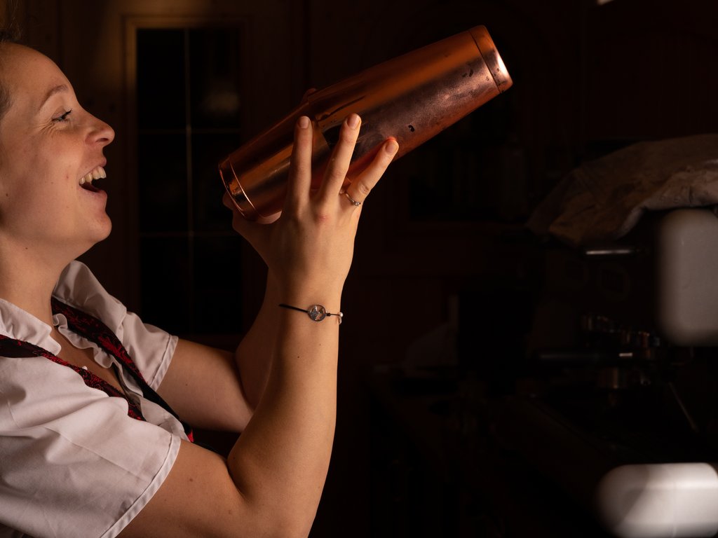 Val di Fassa e ciclabile: da ammirare dal cocktail & tea bar Donna che agita uno shaker da cocktail in un ambiente scuro