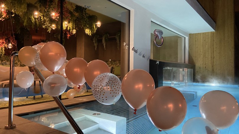 A Soraga il meteo è sempre ottimo per un Day Spa! Palloncini rosa e bianchi decorano una piscina moderna all'interno di una casa di sera