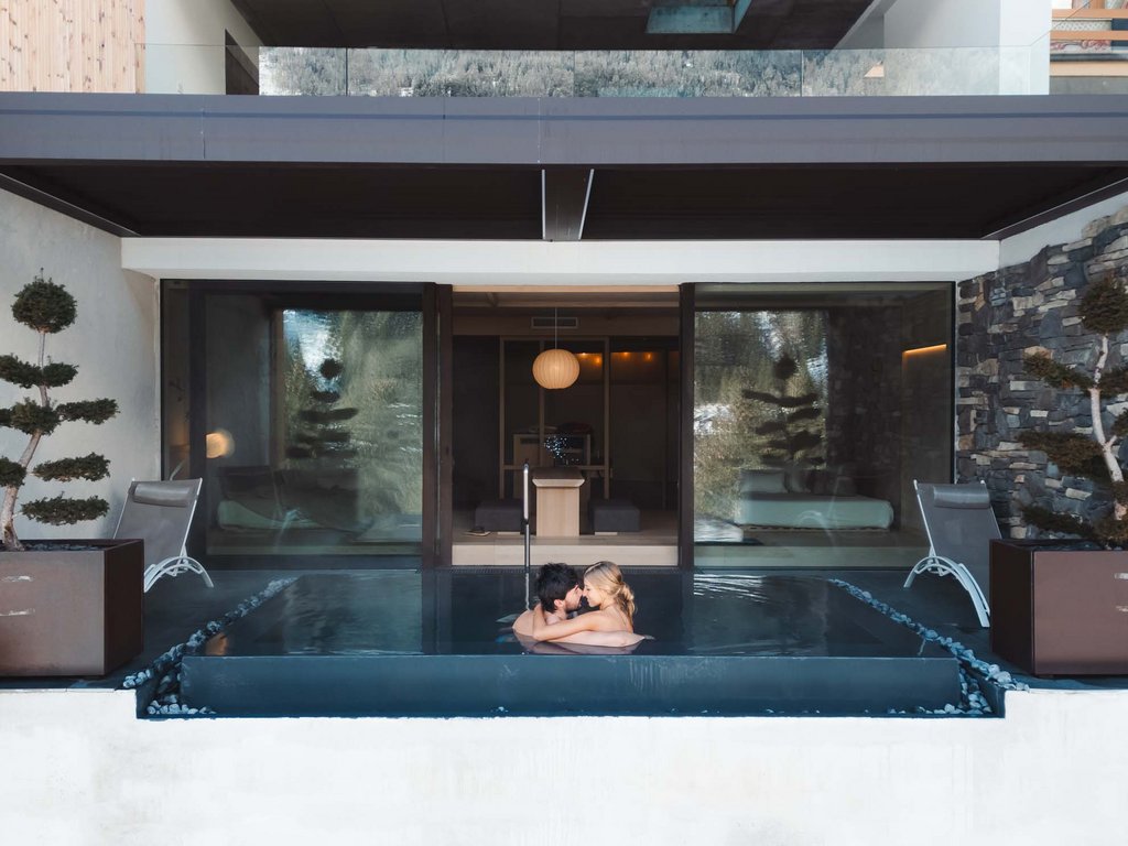 Soraga: dal lago alla piscina del Latemar Coppia abbracciata in una piscina privata all'aperto di un hotel moderno