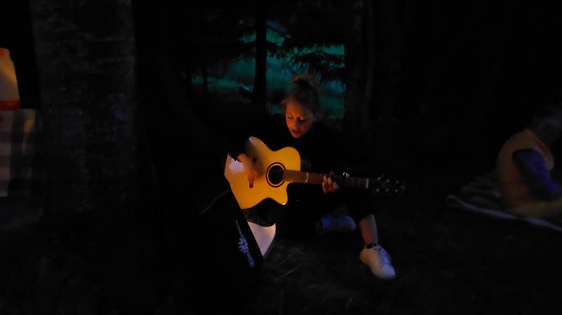 Escursioni da Moena e molto altro: il nostro programma Ragazza che suona la chitarra sotto luci appese di sera in campeggio