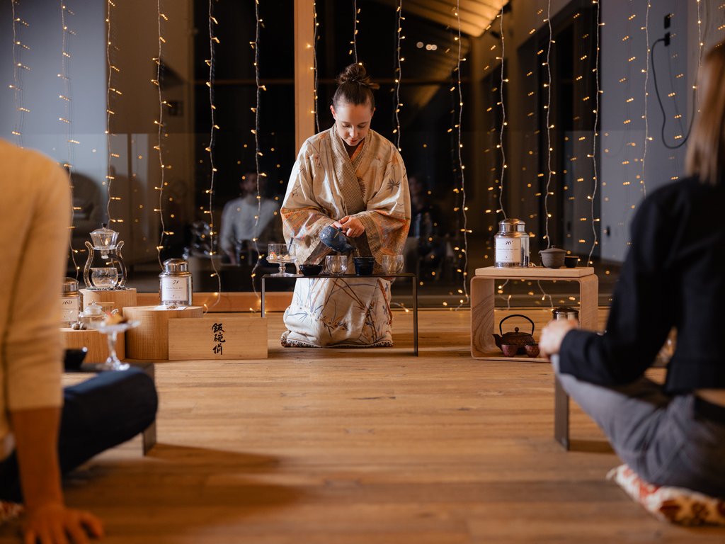 Val di Fassa e ciclabile: da ammirare dal cocktail & tea bar Donna in kimono che prepara una cerimonia del tè giapponese davanti a due persone sedute.