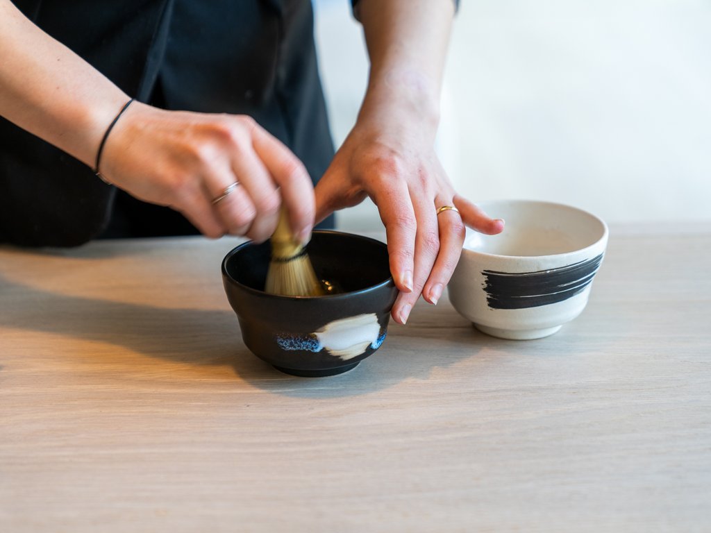 Soraga: dal lago alla piscina del Latemar Persona che prepara il tè verde con frusta in ciotola di ceramica