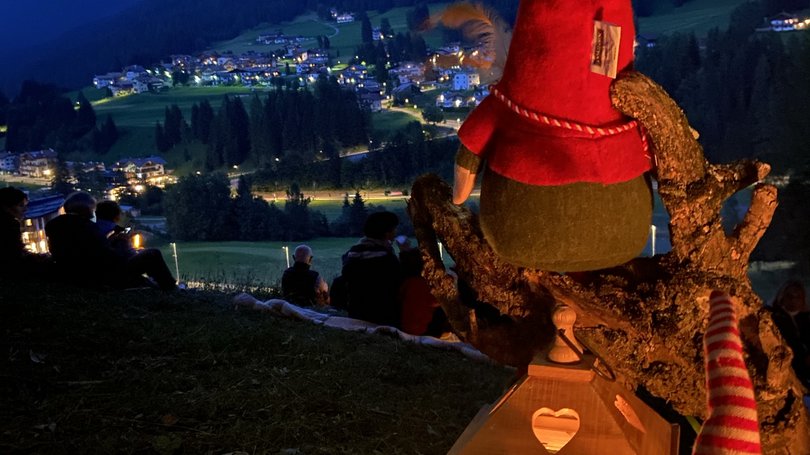 Escursioni da Moena e molto altro: il nostro programma Lanterna accesa e pupazzi con cappelli rossi su collina di sera con vista villaggio illuminato