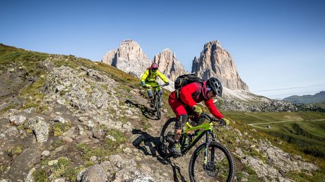 Meteo, Moena, Soraga, Latemar: tutto nella nostra gallery Due ciclisti su mountain bike su sentiero in montagna con Dolomiti sullo sfondo