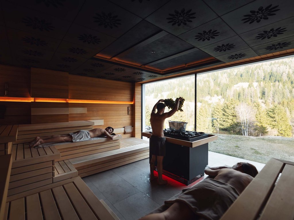 Al Latemar, dopo le passeggiate: relax nella Spa Oniro Persone in sauna con vista panoramica sulla foresta montana