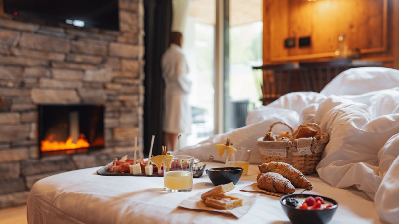 Moena, alberghi da sogno, panorama? C’è l’Hotel Latemar! Colazione in camera con camino acceso e persona in accappatoio vicino alla porta