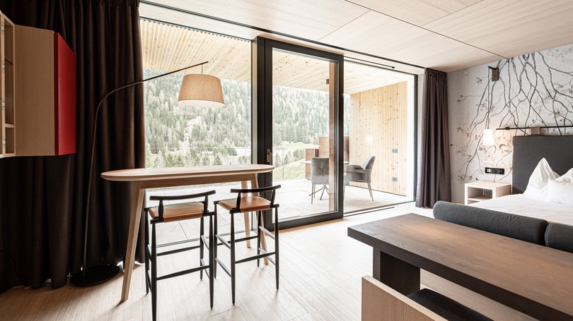 Moena, alberghi da sogno, panorama? C’è l’Hotel Latemar! Interno di una stanza moderna con tavolo, sedie e balcone con vista sulle montagne