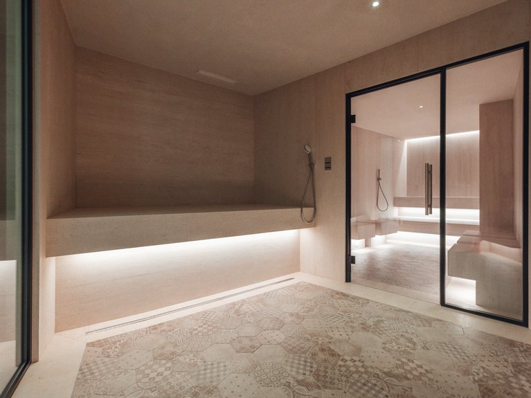 Il rituale dell’hammam al Latemar Hotel Interno sauna moderna con luci soffuse e pareti in legno chiaro