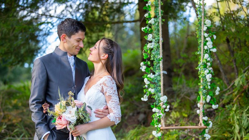 La pista ciclabile in Val di Fassa? C’è molto di più! Coppia di sposi che si abbraccia vicino a un'altalena decorata con fiori bianchi