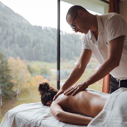 Al Latemar, dopo le passeggiate: relax nella Spa Oniro Massaggiatore che fa un massaggio alla schiena in una stanza con vista sulla montagna