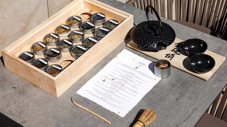 Meteo, Moena, Soraga, Latemar: tutto nella nostra gallery Set per tè con scatola di erbe, teiera nera, tazze e menu su tavolo grigio