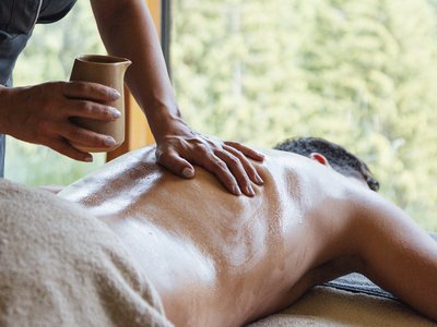 Al Latemar, dopo le passeggiate: relax nella Spa Oniro Massaggio con olio su schiena di un uomo in una stanza con vista natura