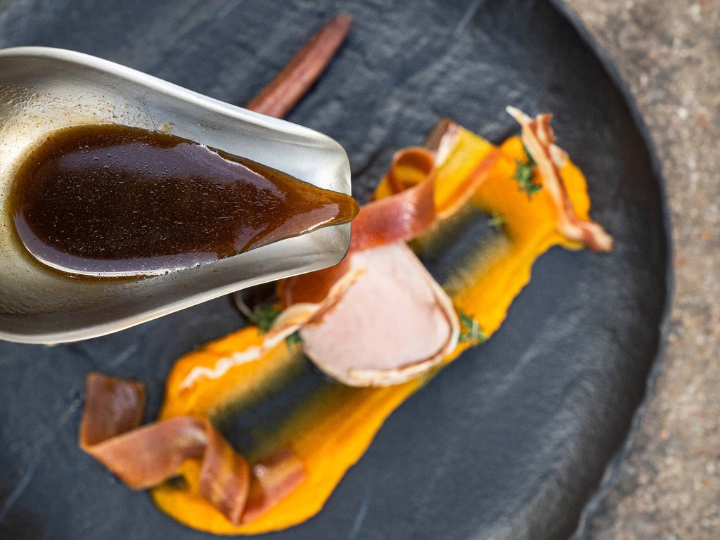 Ristorante gourmet in Val di Fassa: il Mirage al Latemar Salsa versata su piatto con purea arancione e carne decorata