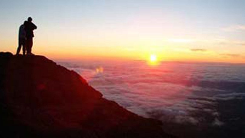 La pista ciclabile in Val di Fassa? C’è molto di più! Persone su una montagna che guardano il tramonto sopra le nuvole