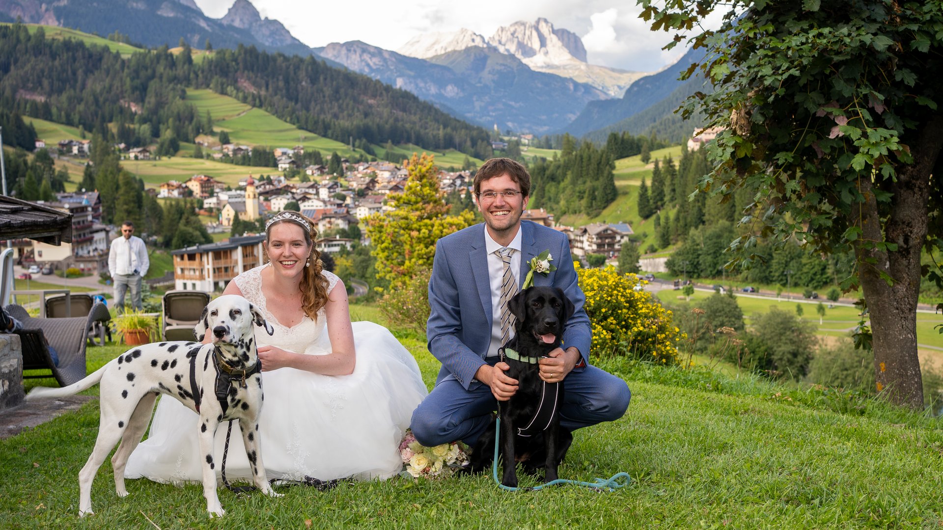 Dalla webcam il Latemar è bello, ma dal vivo è un sogno! Coppia di sposi con due cani in un paesaggio montano verde con villaggio alle spalle