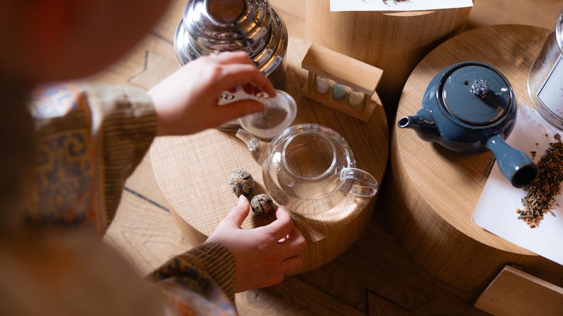 Escursioni da Moena e molto altro: il nostro programma Persona che prepara il tè con teiere e foglie di tè su supporti di legno