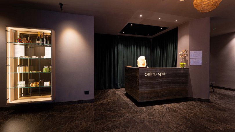 Moena, alberghi da sogno, panorama? C’è l’Hotel Latemar! Reception moderno di una spa con esposizione di prodotti e luci calde