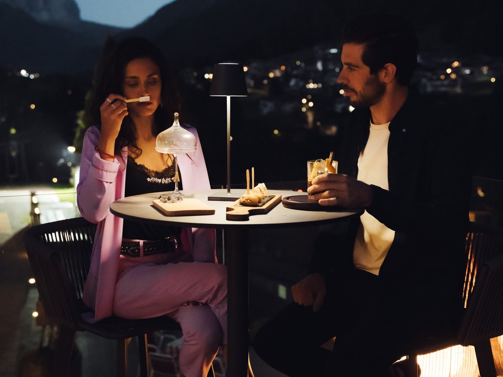 Val di Fassa e ciclabile: da ammirare dal cocktail & tea bar Coppia che cena e beve su un balcone con vista sulle montagne di notte