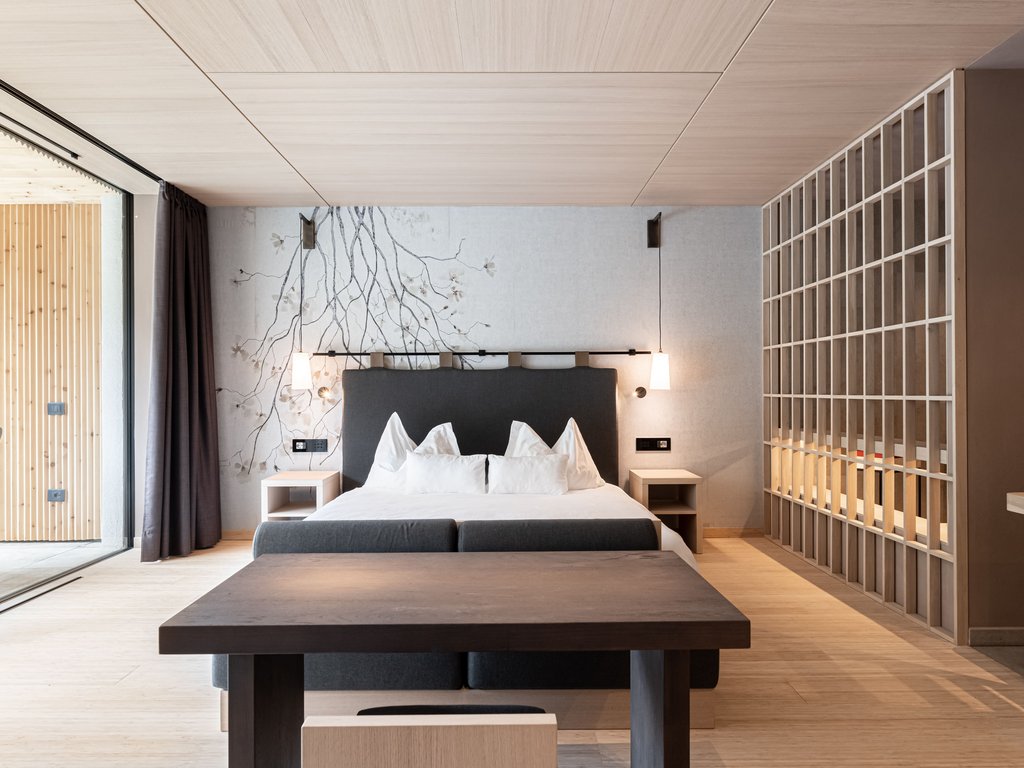 Val di Fassa: dove dormire e vivere vacanze sostenibili Camera da letto moderna con letto matrimoniale e scrivania in legno