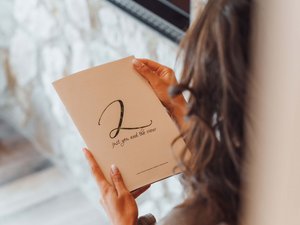 Escursioni da Moena e molto altro: il nostro programma Donna che tiene un libro vicino a un camino acceso in una stanza accogliente.