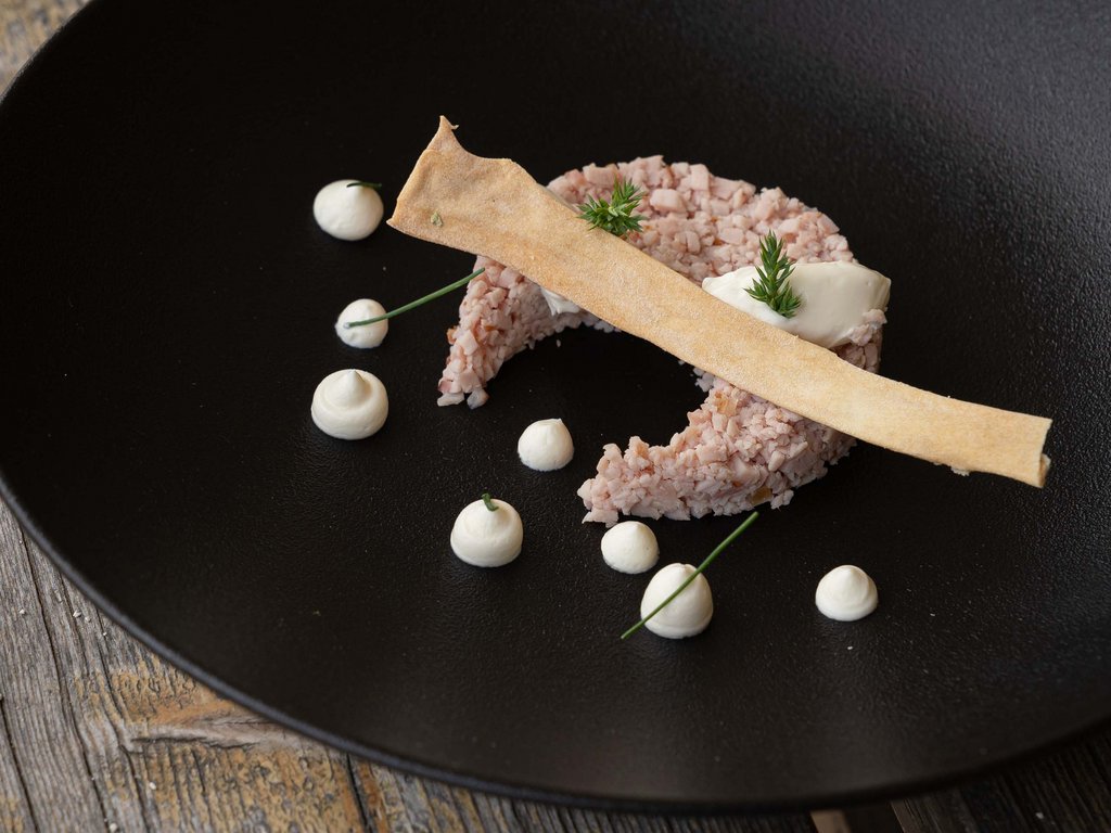 Ristorante gourmet in Val di Fassa: il Mirage al Latemar Piatto elegante con tartare, crema bianca e croccante su piatto nero