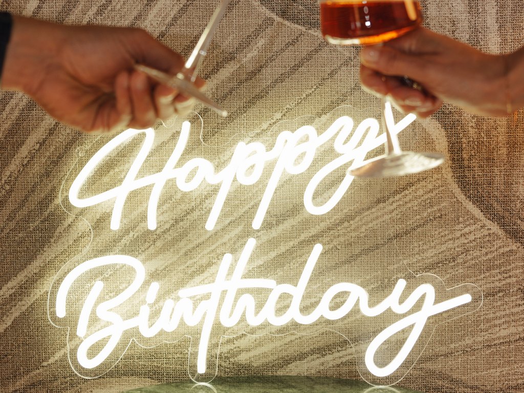 Sulla pista ciclabile, da Moena alla vostra oasi romantica Due mani che brindano con calici di vino davanti a un'insegna al neon Buon Compleanno