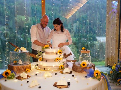 Escursioni da Moena e molto altro: il nostro programma Sposi felici tagliano una torta nuziale con girasoli e luci decorative