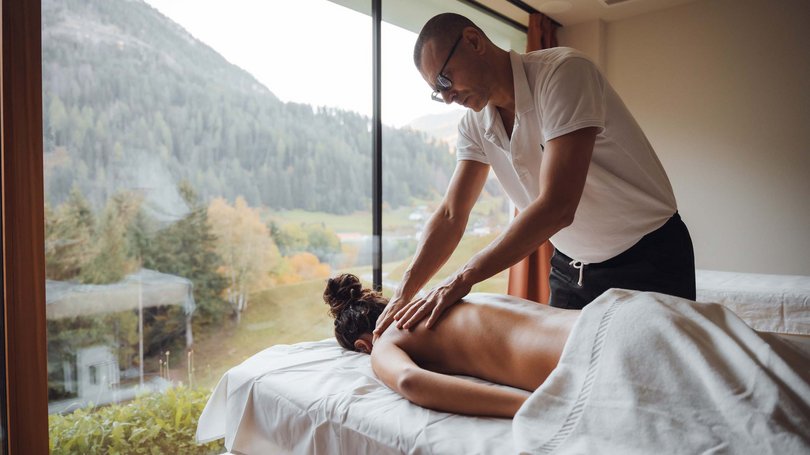 A Soraga il meteo è sempre ottimo per un Day Spa! Uomo che fa un massaggio alla schiena a una donna con vista sulle montagne