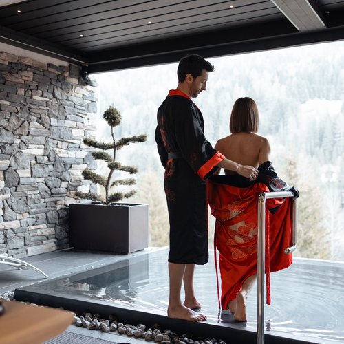Al Latemar, dopo le passeggiate: relax nella Spa Oniro Coppia con kimono che entra in una piscina con vista sulle montagne