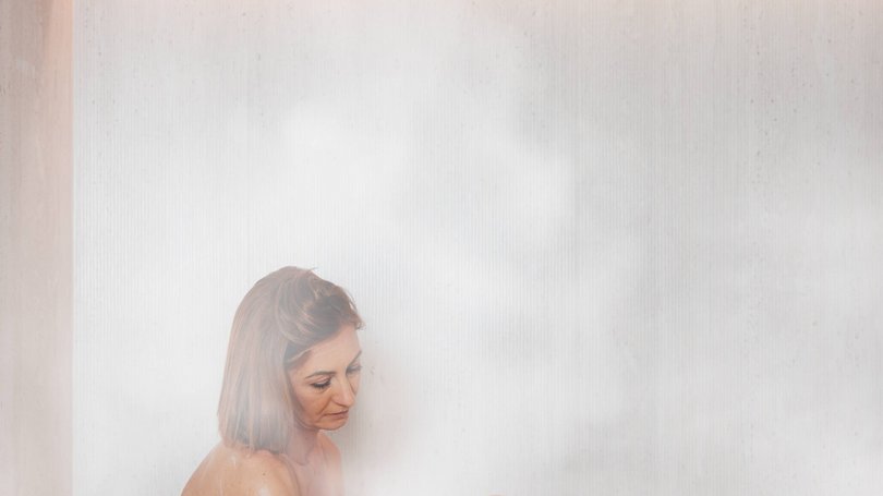 A Soraga il meteo è sempre ottimo per un Day Spa! Donna avvolta in asciugamano che applica lozione in una sauna fumosa